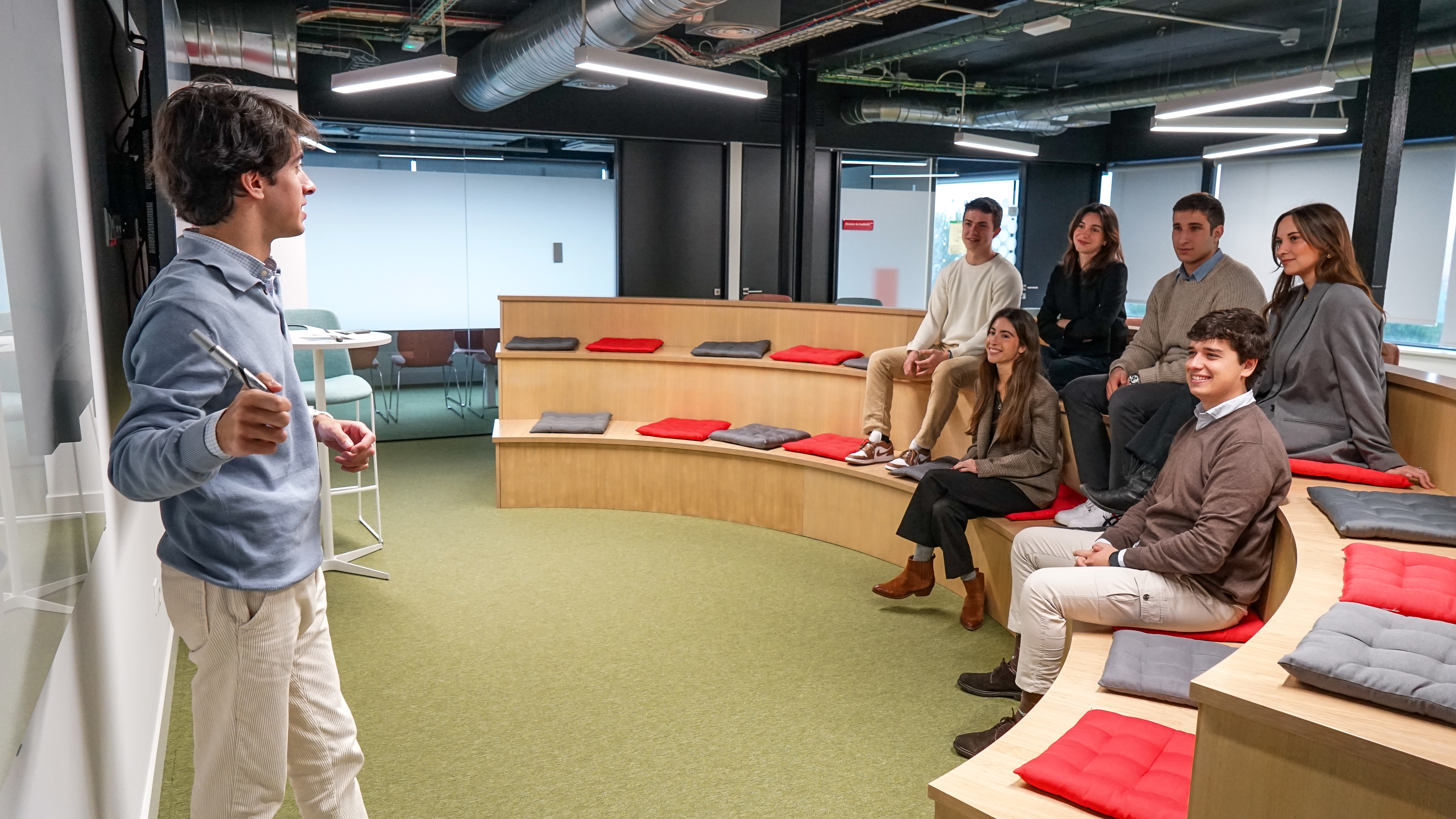 Personas jóvenes en una sala exponiendo una presentación